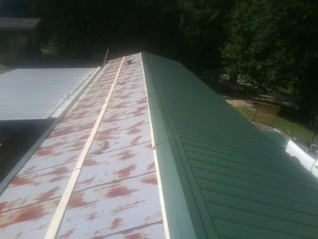 Old rusted panels beside newly installed green metal roofing — Wind Damage Roof Repair by Roofing Brothers in Broadview